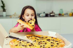 wenig Mädchen mit groß Pizza beim Zuhause foto