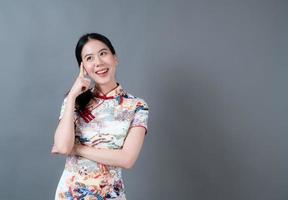 schöne junge asiatische frau trägt chinesisches traditionelles kleid mit der hand, die auf der seite präsentiert