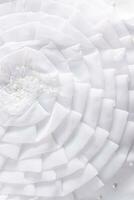 elegant Vertikale Hintergrund von das Braut Hochzeit Kleid Teil. Sanft Falten von ein groß Weiß Seidenraupe Blume. Stickerei mit Perlen. foto