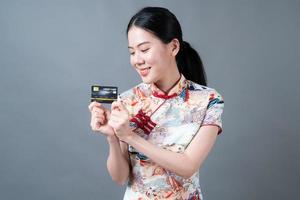 asiatische frau trägt chinesisches traditionelles kleid mit hand, die kreditkarte hält foto