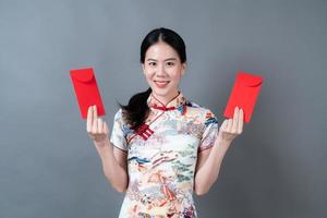 asiatische Frau trägt chinesisches traditionelles Kleid mit rotem Umschlag oder rotem Paket
