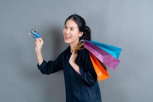 schöne asiatische Frau mit Einkaufstüten und mit Kreditkarte showing