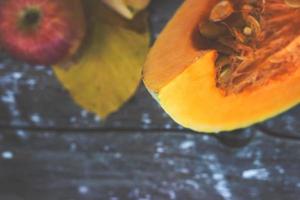 Saisonale Tapete - Draufsicht auf Kürbisscheibe und Apfel auf dunklem Holzhintergrund