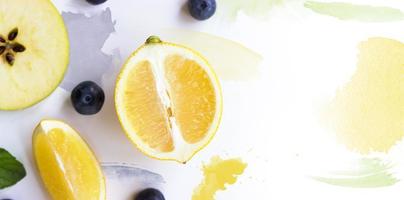 Zitrone, Apfel und Blaubeeren auf weißem Hintergrund mit Aquarellstrichen kreatives Layout mit Kopierraum foto