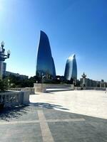 Baku Stadt Panorama- Aussicht , Hauptstadt von Aserbaidschan. sonnig Tag. Stadt Wolkenkratzer. groß breit Tratoir mit schön Balustrade und Straßenlichter. modisch modern Gebäude inmitten Blau Himmel. Vertikale foto