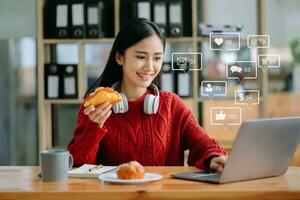 asiatisch Frau Tippen Smartphone, Tastatur mit Laptop Computer von Sozial Medien und Marketing virtuell Symbole Bildschirm Konzept. foto