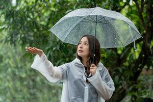 asiatisch schön Frau halten Regenschirm im regnet Jahreszeit foto