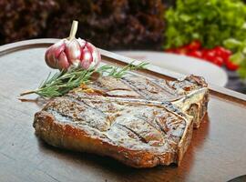 t Knochen Steak mit Garnituren, Kartoffel, Salat, Orange Saft, Brot foto