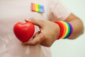 asiatisch Frau halten rot Herz mit Regenbogen Flagge, lgbt Symbol Rechte und Geschlecht Gleichwertigkeit, lgbt Stolz Monat im Juni. foto