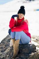 blonde frau, die im winter auf einem felsen in den schneebedeckten bergen sitzt, in sierra nevada, granada, spanien. foto