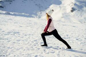 Frau Dehnen Beine im schneebedeckt Terrain foto