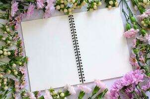 leeren Weiß Notizbuch und Bleistift mit Rosa Blumen auf Weiß Hintergrund. foto