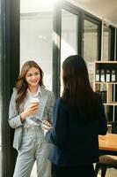 glücklich zwei asiatisch Geschäft Frau halten Kaffee Tasse im Coworking Büro foto