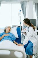 kaukasisch Arzt lächelnd nehmen Pflege von ein Senior geduldig im Krankenhaus. freundlich Krankenschwester oder therapeutisch behandeln Klient Fachmann medizinisch Bedienung Konzept. foto
