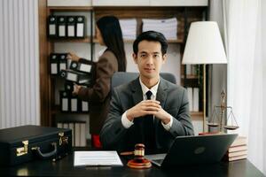 asiatisch Anwalt Mann Arbeiten mit ein Laptop und Tablette im ein Gesetz Büro. legal und legal Bedienung Konzept. suchen beim Kamera im modern Büro foto