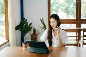 asiatisch Frau Arbeiten im das Büro mit Arbeiten Notizblock, Tablette und Laptop Unterlagen foto