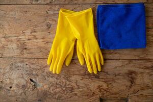 Blau Handtuch und Gelb Handschuhe wurden platziert auf hölzern Tabelle zum Reinigung Mitarbeiter zu verwenden zu sauber und verhindern Reiniger von Dermatitis. Konzept von wählen Reinigung Unternehmen zu sauber das Büro foto