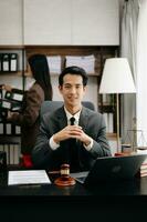 asiatisch Anwalt Mann Arbeiten mit ein Laptop und Tablette im ein Gesetz Büro. legal und legal Bedienung Konzept. suchen beim Kamera im modern Büro foto