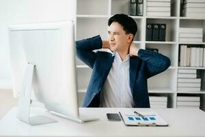 überarbeitet jung asiatisch Geschäftsmann Büro Arbeiter Leiden von Hals Schmerzen nach hätten ein lange Tag beim ihr Büro Schreibtisch. Büro Syndrom Konzept foto