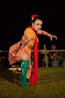 balinesische frau im traditionellen orangefarbenen kleid, das mit einem roten schal tanzt, während es tanzt foto