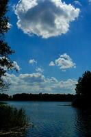 Sommer- idyllisch Landschaft mit ein See unter ein Blau Himmel auf ein warm sonnig Tag foto