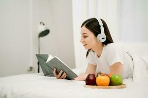 Porträt von gut gesund jung Frau lesen Buch und ruhen im Bett beim Schlafzimmer. Lebensstil Konzept foto