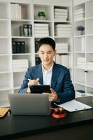 attraktiv jung Anwalt im Büro Geschäft Mann und Anwälte diskutieren Vertrag Papiere Laptop und Tablette mit Messing- Rahmen auf Schreibtisch im modern Büro. Gesetz, legal Dienstleistungen, Beratung, foto