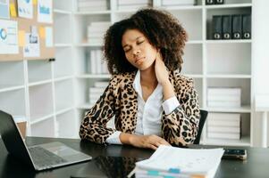 überarbeitet jung afrikanisch Geschäftsfrau Büro Arbeiter Leiden von Hals Schmerzen nach hätten ein lange Tag beim ihr Büro Schreibtisch. foto