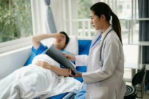 Arzt diskutieren Behandlung mit männlich geduldig reden und Lachen Sitzung auf Untersuchung Bett im Klinik oder Krankenhaus foto