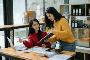 zwei attraktiv jung asiatisch weiblich Hochschule Studenten Arbeiten auf das Schule Projekt mit Laptop Computer und Tablette zusammen, genießen reden foto