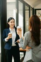 glücklich zwei asiatisch Geschäft Frau halten Kaffee Tasse im Coworking Büro foto