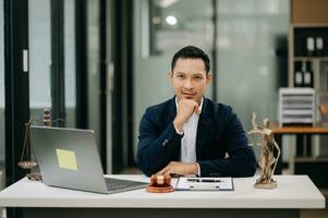 Gerechtigkeit und Gesetz Konzept .asiatisch männlich Richter im ein Gerichtssaal auf Tabelle und Berater Arbeiten im modern Büro. foto