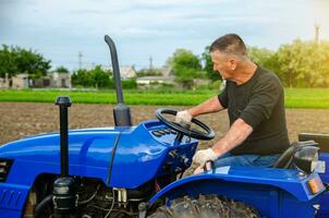 ein Farmer ist Fahren ein Traktor. Agro Industrie, Landwirtschaft. Landwirtschaft, Landwirtschaft. Landschaft Ackerland. klein Bauernhöfe. Arbeit im das landwirtschaftlich Industrie. foto