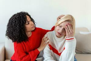 Freund versuchen zu Ruhe Nieder ihr Freund. Frau Weinen. jung Dame Teilen ihr Problem mit Freund. weiblich im Depression. Frau wohltuend er ist traurig Freund Sitzung auf ein Couch im das Leben Zimmer beim Zuhause foto