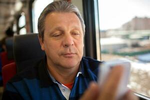 Mann mit Handy, Mobiltelefon Telefon während Zug Reiten foto