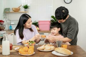 Familie Zeit, Frühstück, Aktivitäten zusammen während das Feiertage. Eltern und Kinder sind haben ein Mahlzeit zusammen während das Feiertage. Neu Zuhause zum Familie auf Morgen, genießen, Wochenende, vakant Zeit foto