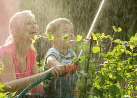 Mutter und ihr jung Sohn spielen mit Wasser foto