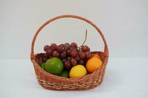 Früchte im ein Korb auf ein Weiß Hintergrund. orange, Traube, Zitrone. foto