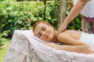 jung schön Frau entspannend im Spa Massage draußen im tropisch Garten. foto