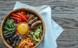 Schüssel von bibimbap auf das hölzern Tabelle foto