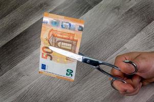 Mann schneidet 50-Euro-Banknoten mit einer Schere foto
