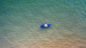 Luftaufnahme von oben auf das Kajakfahren auf dem Meer mit smaragdblauem Wasser und Wellenschaum foto