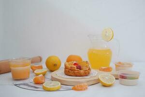 hausgemacht Zitrone Torte mit frisch Obst und Orange Saft auf Weiß Hintergrund foto