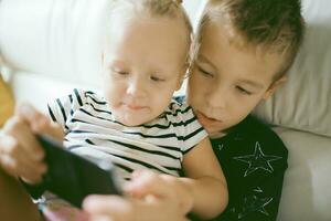 Geschwister spielen Spiele auf Smartphone foto