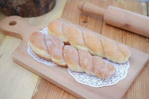 Brot Donuts auf das hölzern Tabelle mit hölzern rollen Stift. foto