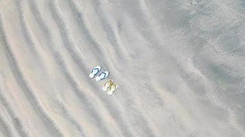 Flip-Flops am Sandstrand, Sommerferienhintergrund, Luftdraufsicht foto