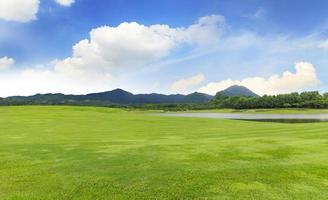 Golfplatz mit grünem Gras und Bäumen im wunderschönen Park unter blauem Himmel foto