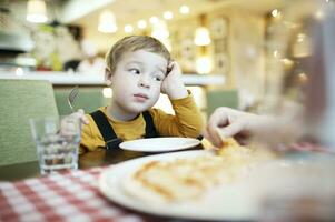 gelangweilter kleiner Junge in einem Restaurant foto