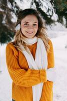 Teen blond im ein Gelb Sweatshirt draußen im Winter. ein Teenager Mädchen auf ein gehen im Winter Kleider im ein schneebedeckt Wald foto