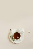 Flache Lage der Teetasse mit Apfelblumen und Marshmallow auf beigem Hintergrund mit Kopierraum foto